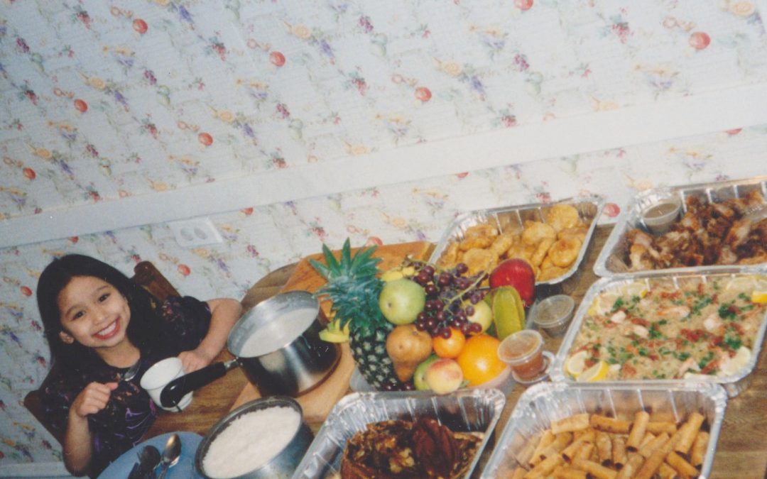 Katherine, age 7, celebrating New Year's Eve with a feast of Filipino foods. It is a New Year's Eve tradition to display 12 round fruits to attract prosperity for the coming year.