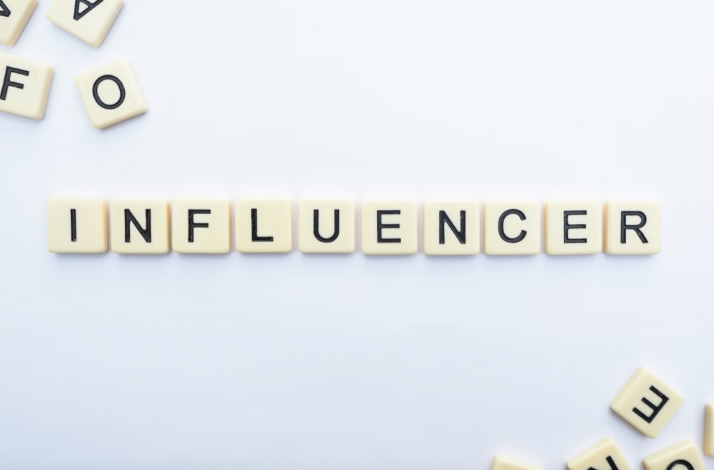 Scrabble tiles spelling out the word "influencer", off white background