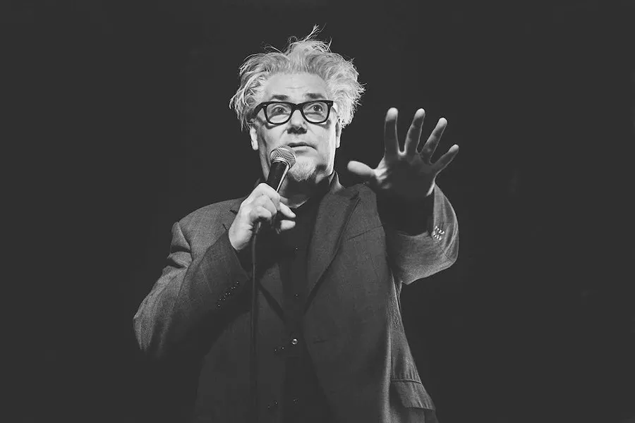 Martin Atkins holding a microphone, black and white picture with an all black background